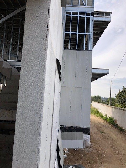 Mur extérieur et structure métallique d’un bâtiment en construction avec isolation et ossature apparente.